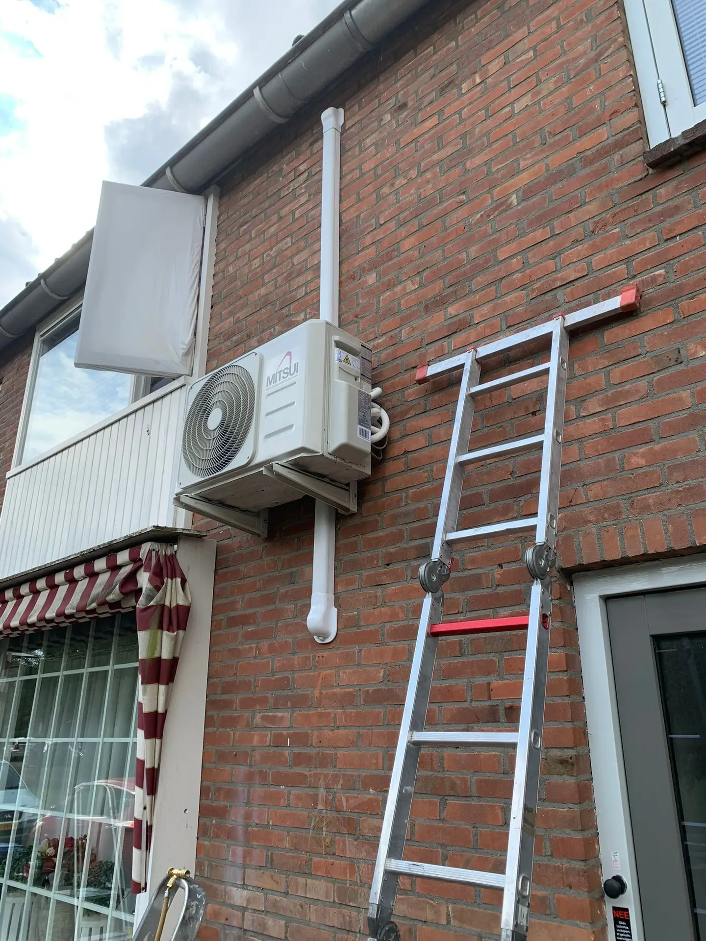 Mitsui buitenunit aan gevel met witte koof